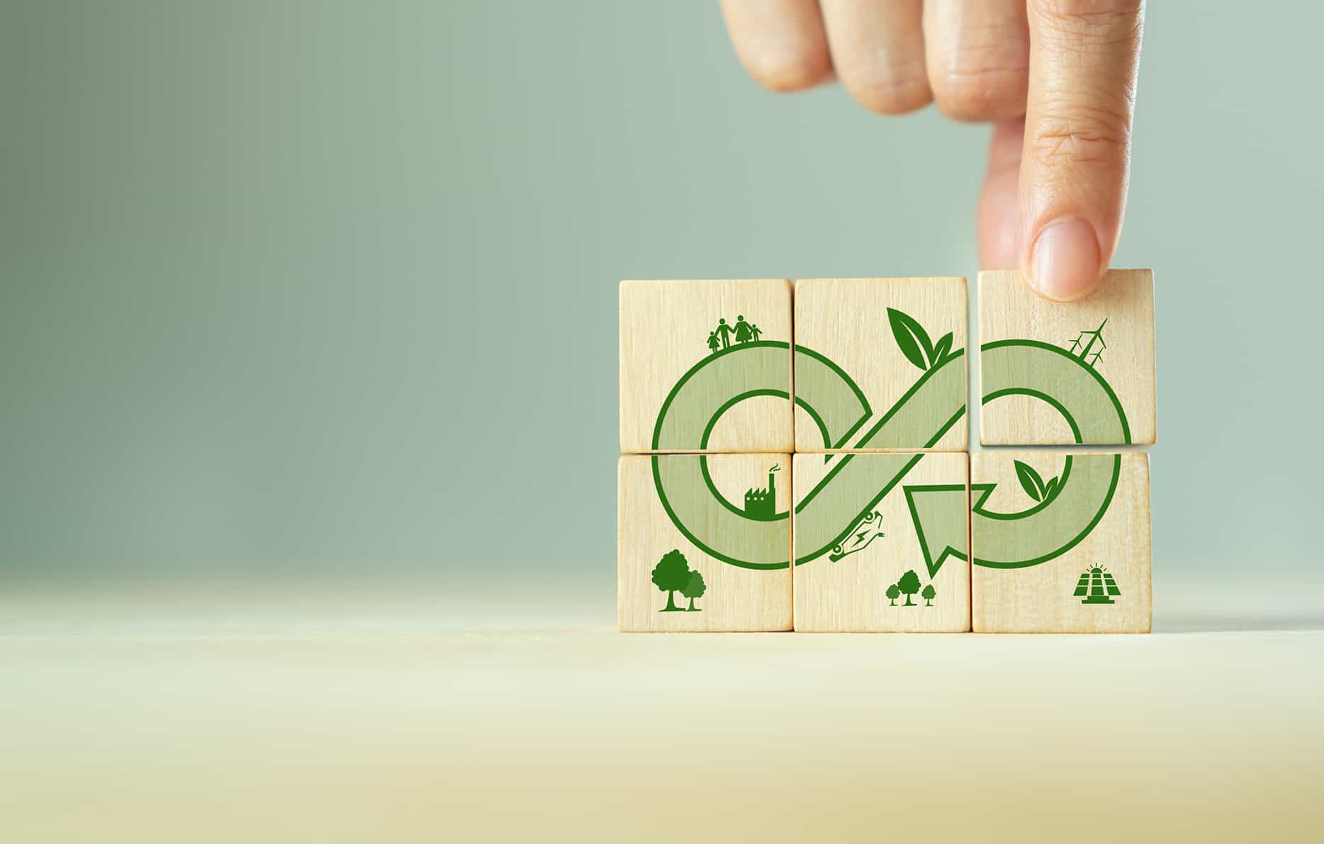 Green eco infinity, net zero, circular economy, renewable enwergy and save the world concept. Sustainable development. Hand puts wooden cubes with green econ infinity on grey background. Eco banner.